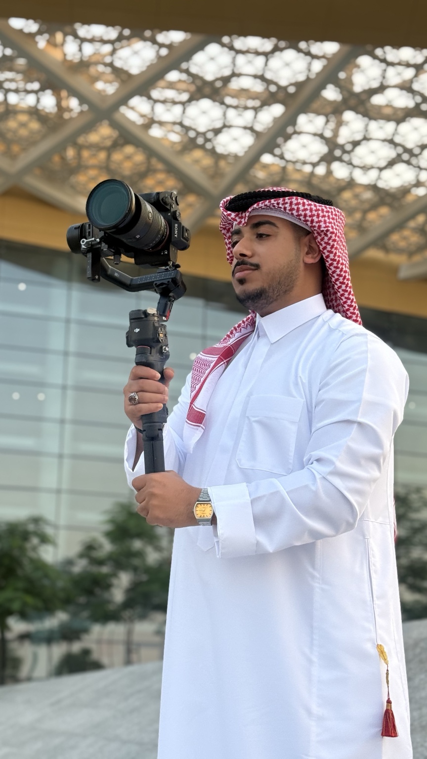 مصوّر نكست شوت بالزيّ الخليجي يحمل كاميرا Sony على مثبّت DJI أثناء تصوير ميداني